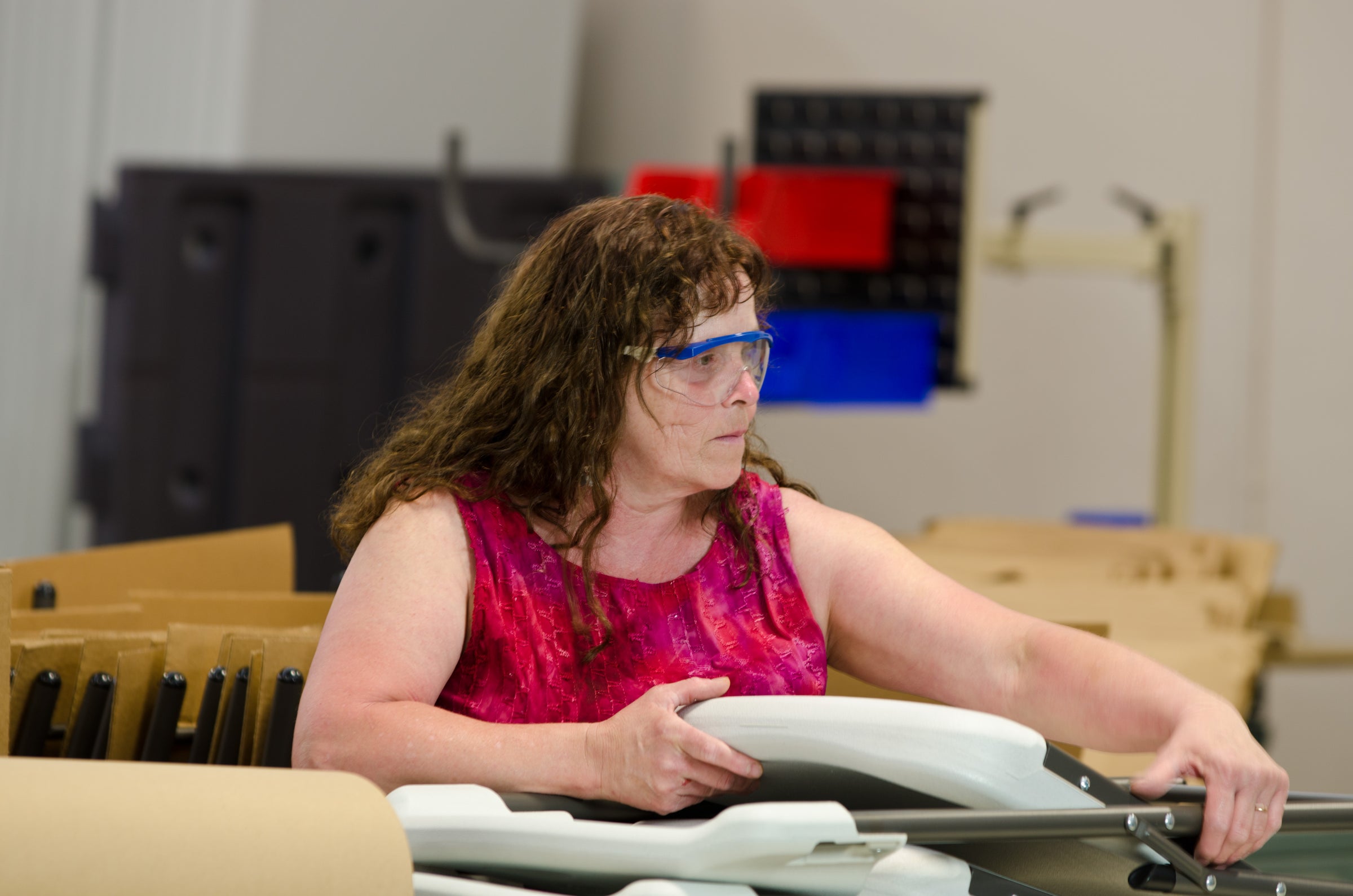 Woman wearing a pink shirt packaging a chair.