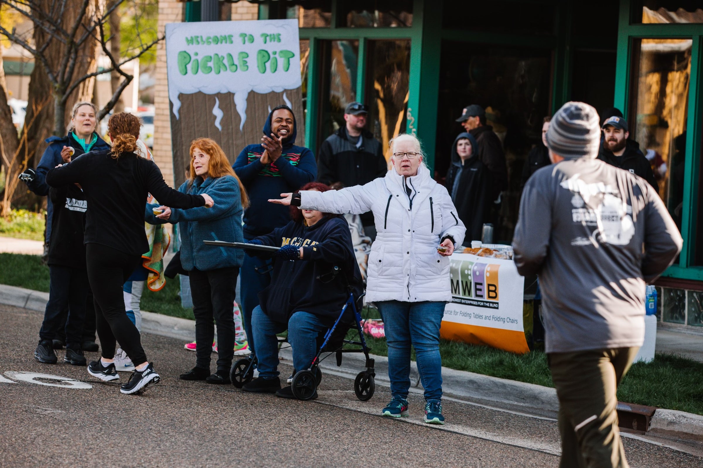 A picture of a group of people standing around the Pickle Pit sign.