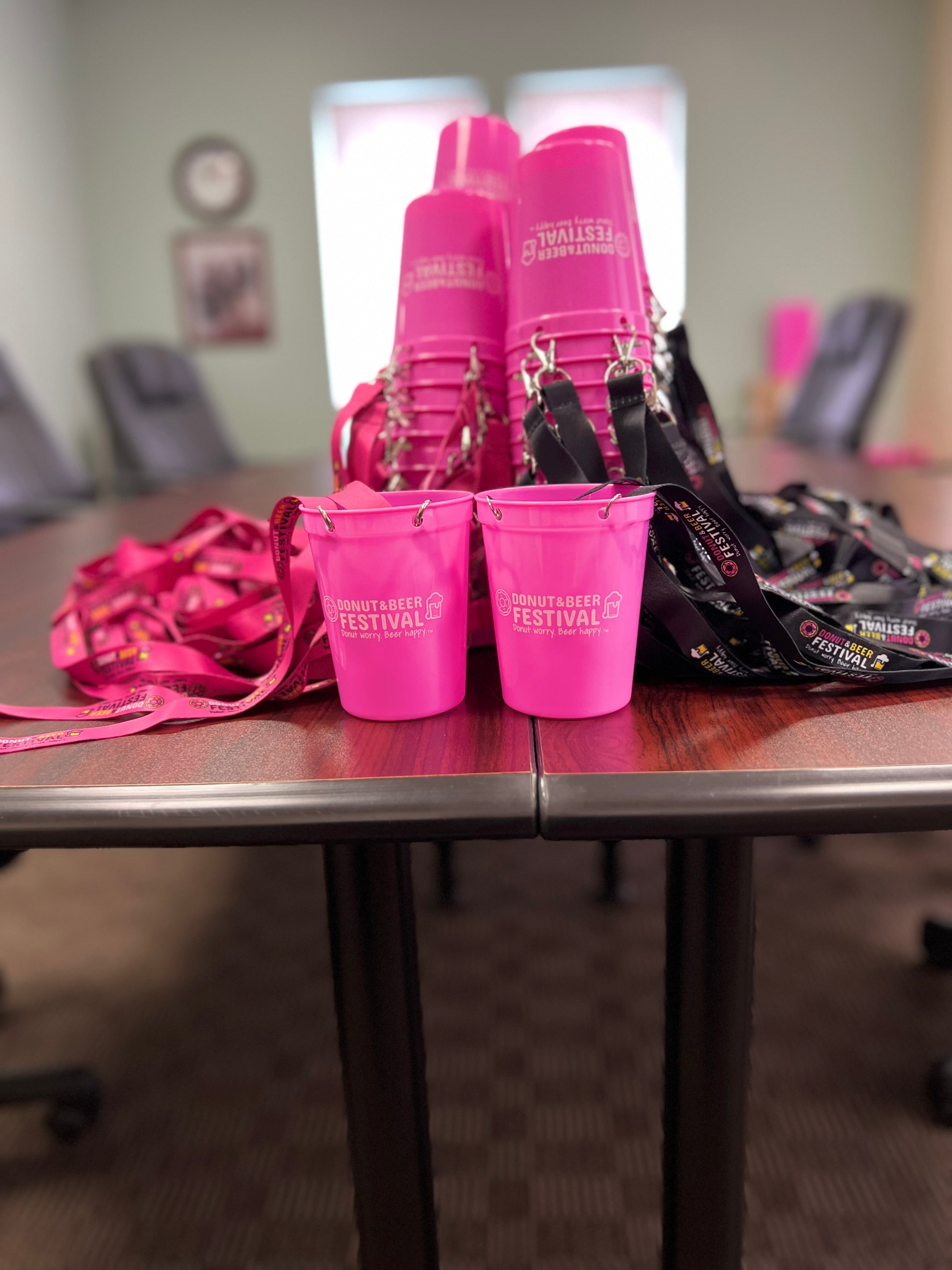A picture of pink cups and pink and black lanyards attached to them. 