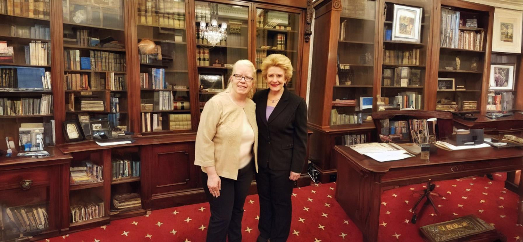 A picture of two women in a well set up room with red carpet.